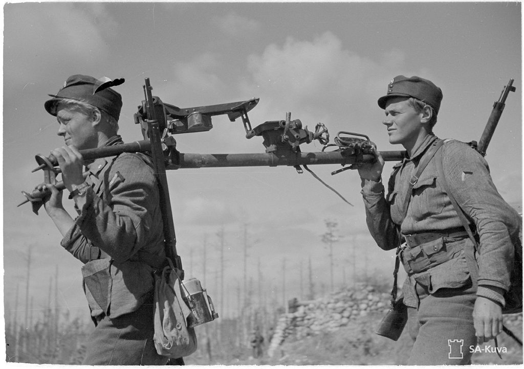 Miehet kantamassa konekiväärin jalustaa. Summan lohko 18.6.1944. (SA-kuva)