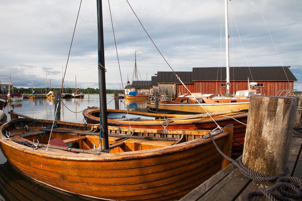 Puisia purjeveneitä satamassa Ahvenanmaalla. Taustalla puisia venekoppeleita.